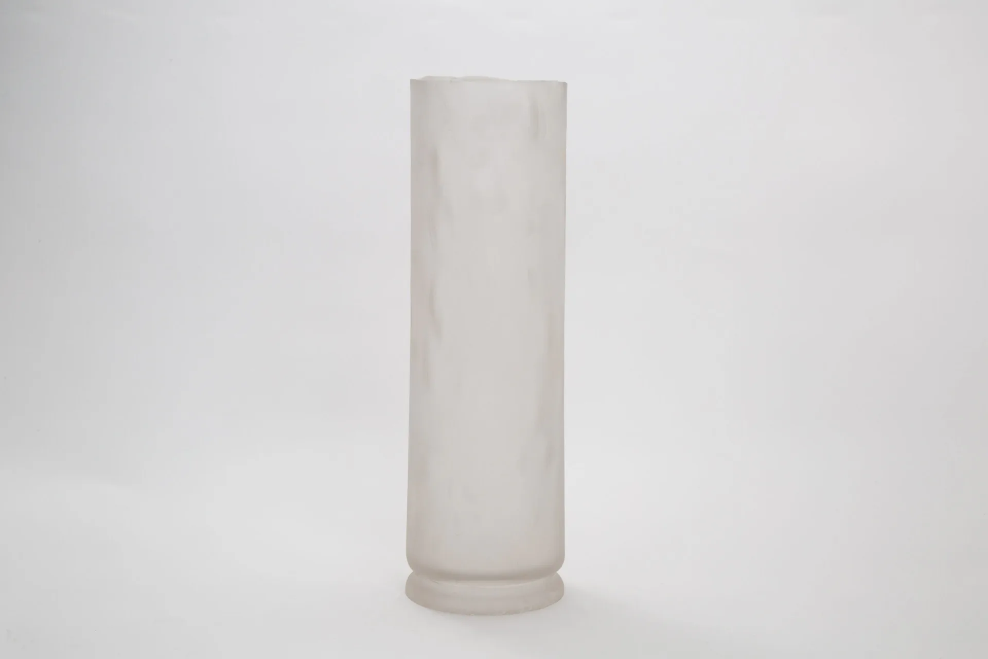 Minimalist white cylindrical vessel with subtle base detail against neutral background, by MDSG Studio.