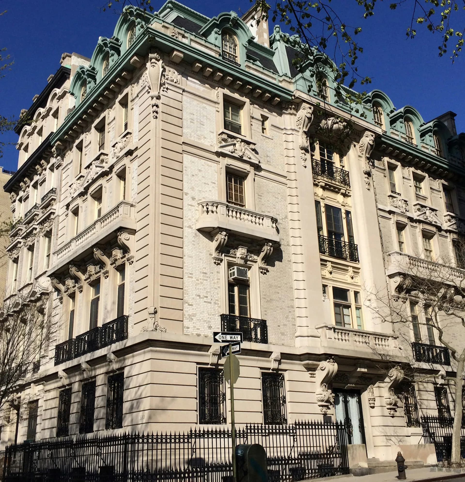 Cream-colored Haussmann-style Parisian building facade with mansard roof, ornamental stonework, and wrought-iron balconies by MERGAL ARCHITECTURE & DESIGN.