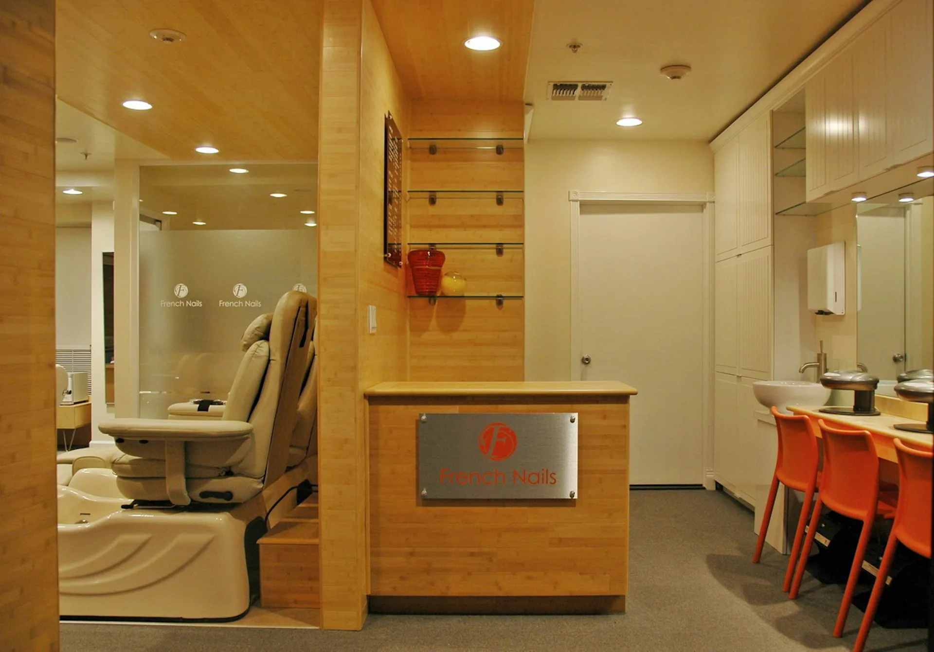 Modern commercial interior with wood-paneled partition, integrated seating area, red accents, and mirrored bathroom facilities by Metropolitan United Studio, PLLC.