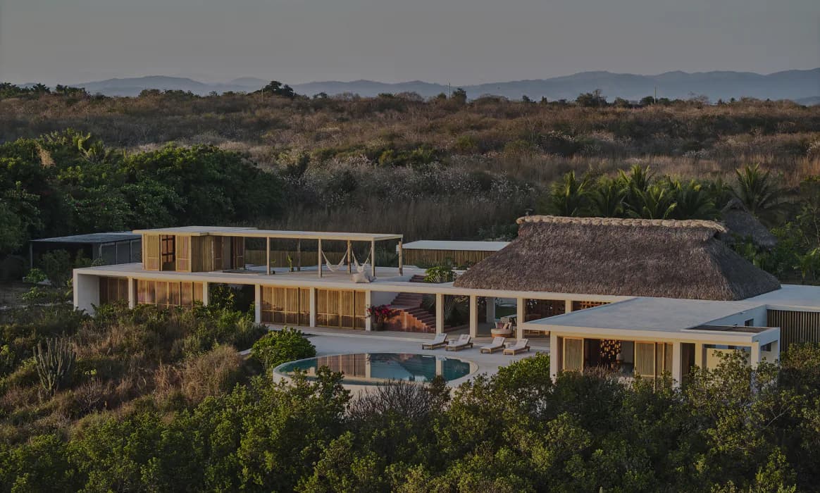Modern residential architecture nestled in hillside landscape with warm wood cladding, large glazing, and integrated outdoor spaces by Meyer Davis.
