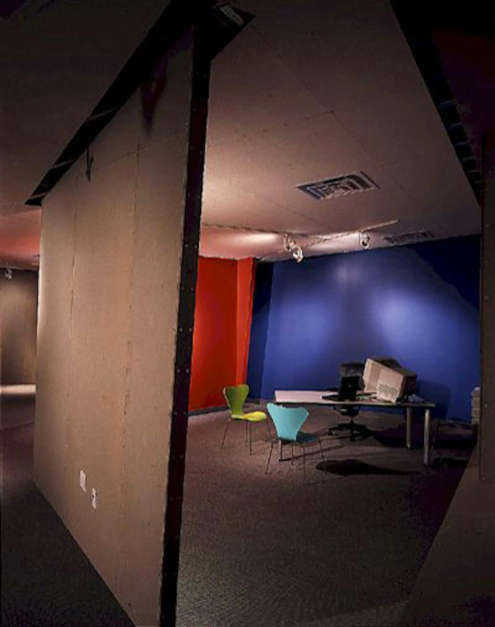 Modern office interior with bold red and blue accent walls, contemporary furniture, and exposed ceiling elements by Michael McDonough Architect.