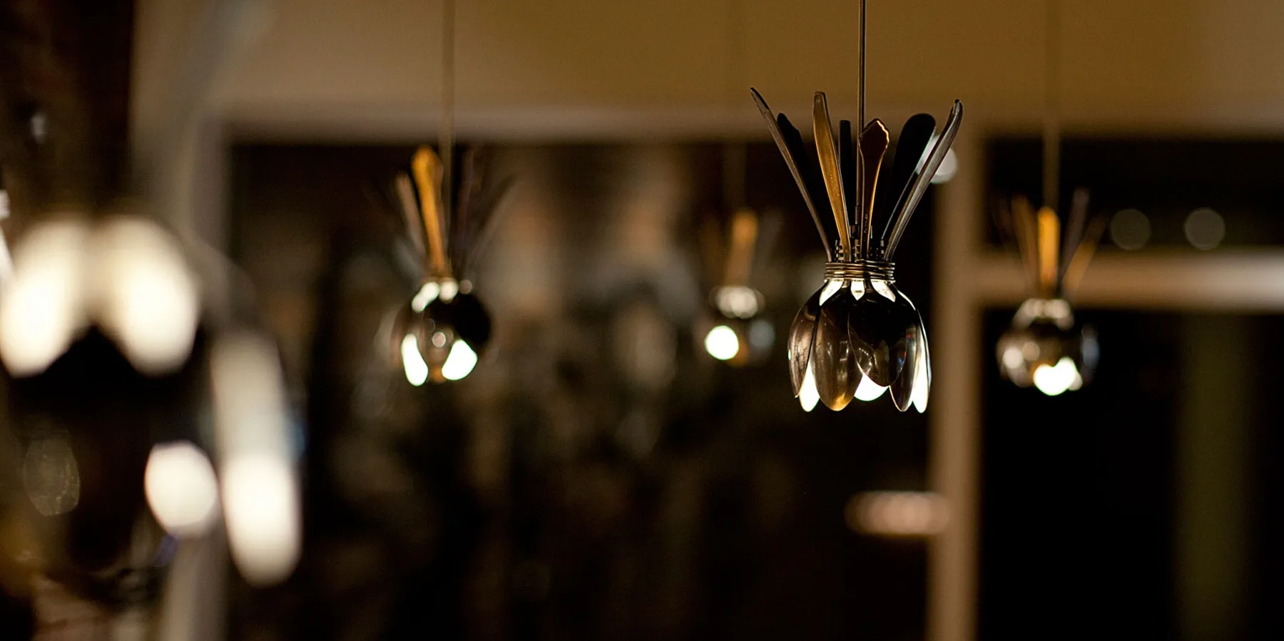 Elegant pendant lighting installation featuring glass and metal fixtures with warm golden illumination suspended in a contemporary interior by Michiru Tanaka Lighting Design.