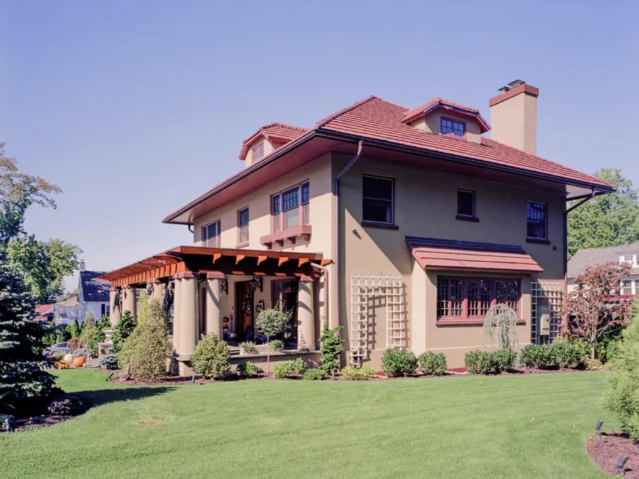 Cream-colored Mediterranean Revival mansion with terracotta tile roof, arched portico, and manicured lawn, designed by Mitropoulos Architects.