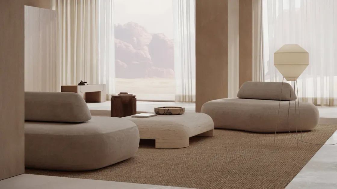 Minimalist lounge interior with curved modular seating, neutral beige palette, natural materials, and floor-to-ceiling windows overlooking mountains by Monolith.