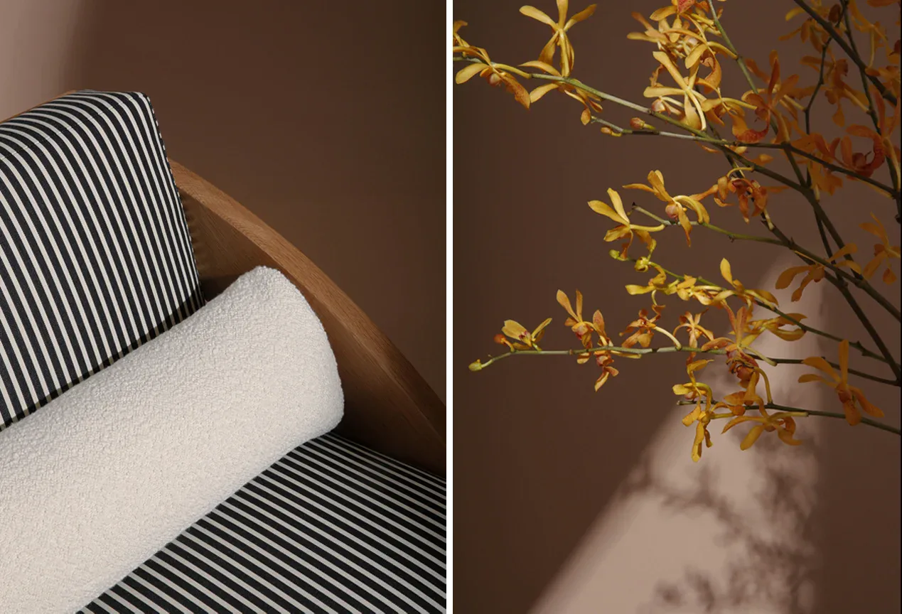 Split-view interior detail showing striped upholstered seating and dried botanical arrangement with warm natural light casting shadows, by Moving Mountains.