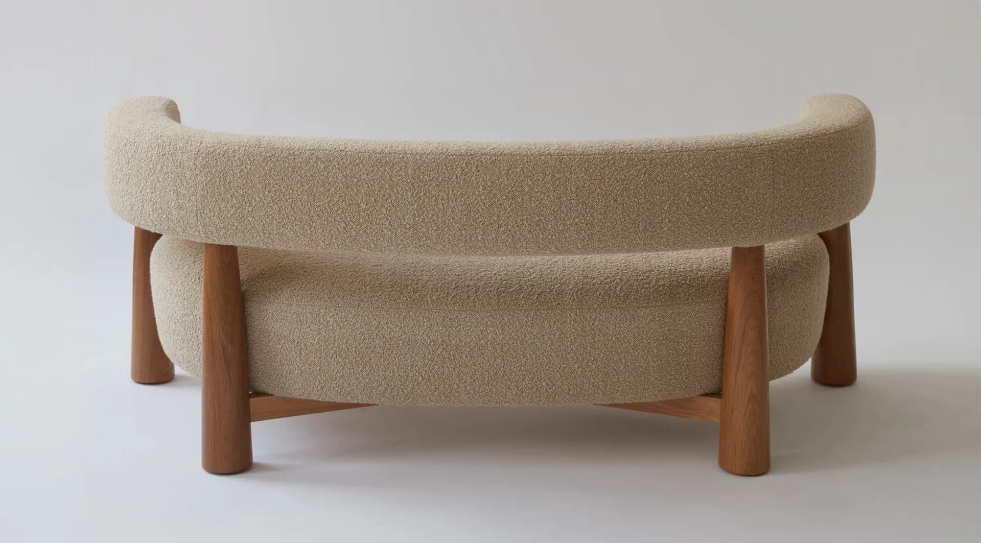 Beige upholstered curved bench with wooden legs and frame detail, shown against neutral background by Moving Mountains.