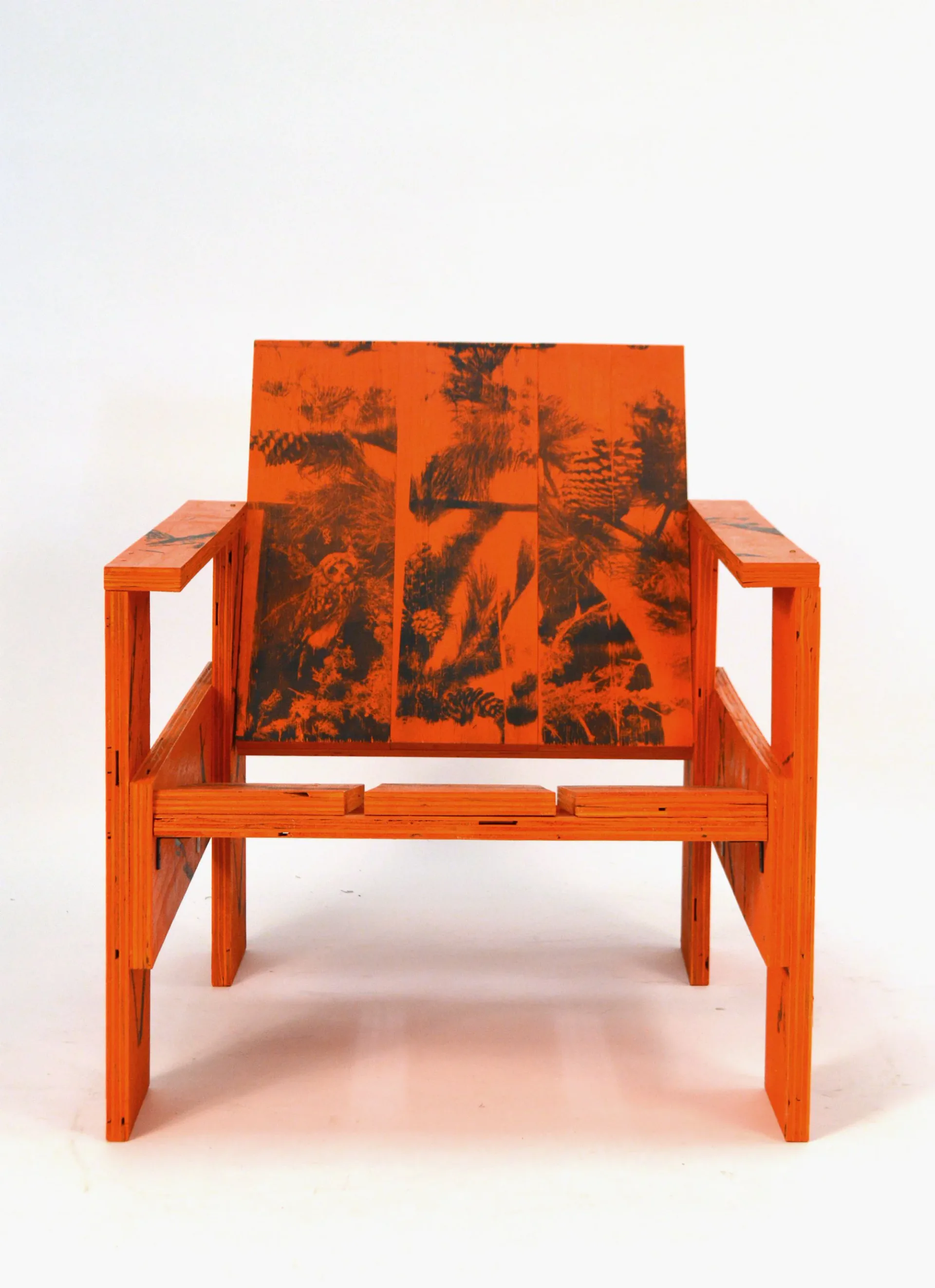 Bright orange wooden armchair with black botanical illustration upholstery, shown against a white background by MTM Studio.