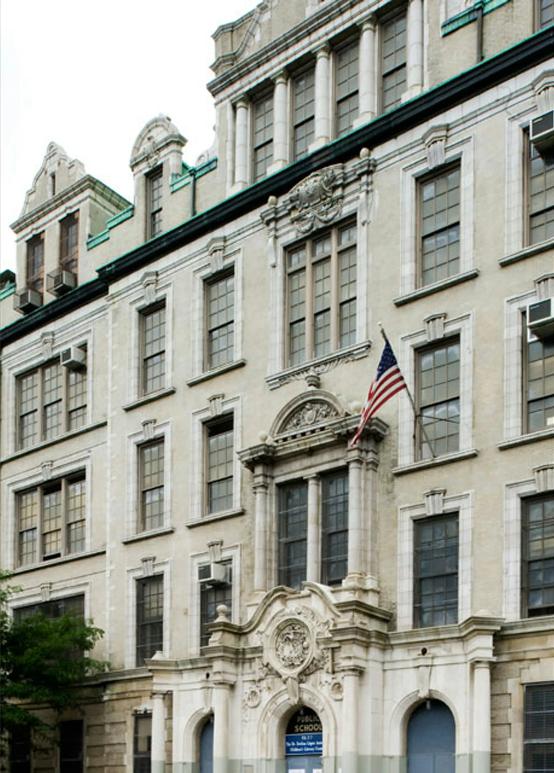 Classical six-story limestone facade with mansard roofline, ornate stonework, and American flag, renovated by Nelligan White Architects.