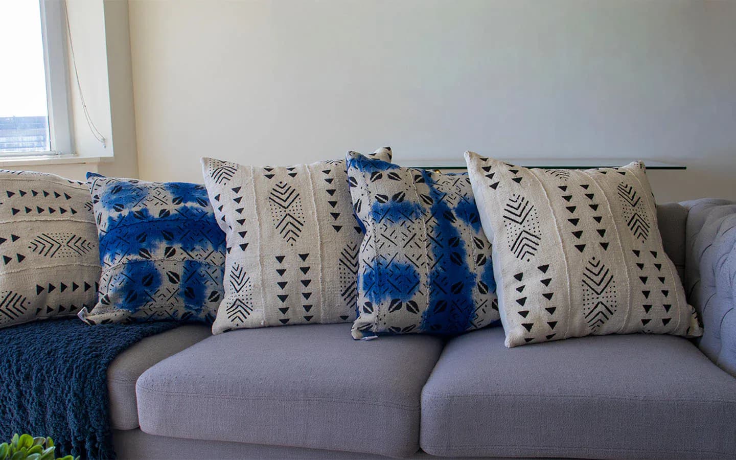 Gray upholstered sofa styled with patterned throw pillows in blue and cream tones and geometric-printed accent pillows by Niche Handmade Furniture.