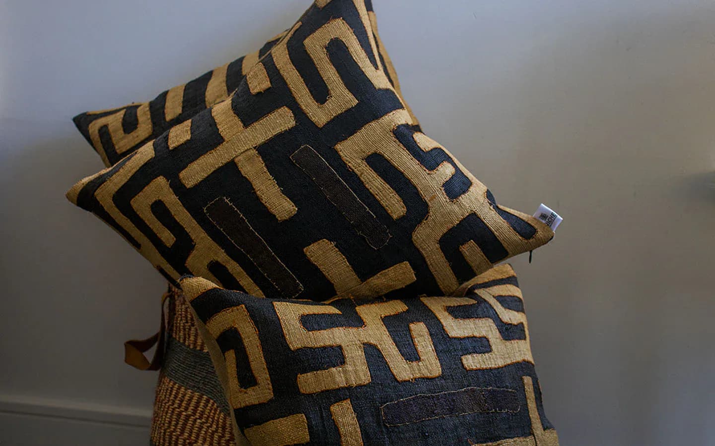 Stacked decorative pillows featuring bold geometric patterns in black and gold fabric, showcasing textile design by Niche Handmade Furniture.