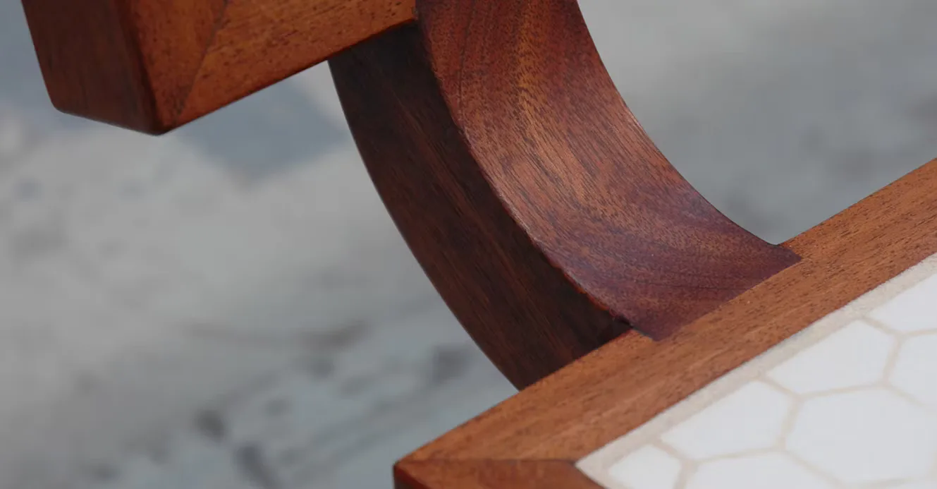Close-up detail of curved wooden furniture or architectural element with warm reddish-brown tones and smooth sculpted surfaces by Nine Stories.