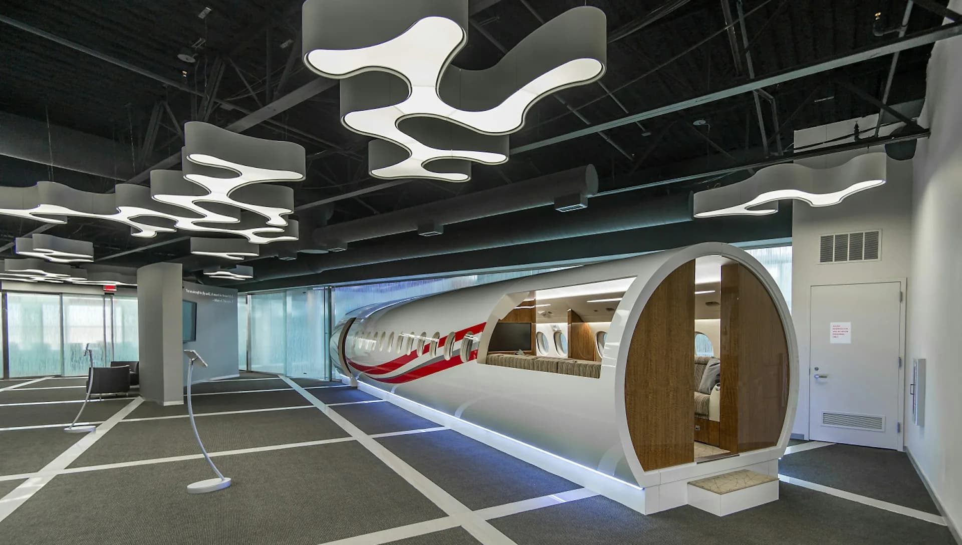 Modern office lounge with sculptural white ceiling lights, curved pod seating, and blue accent stripe by NK Architects.