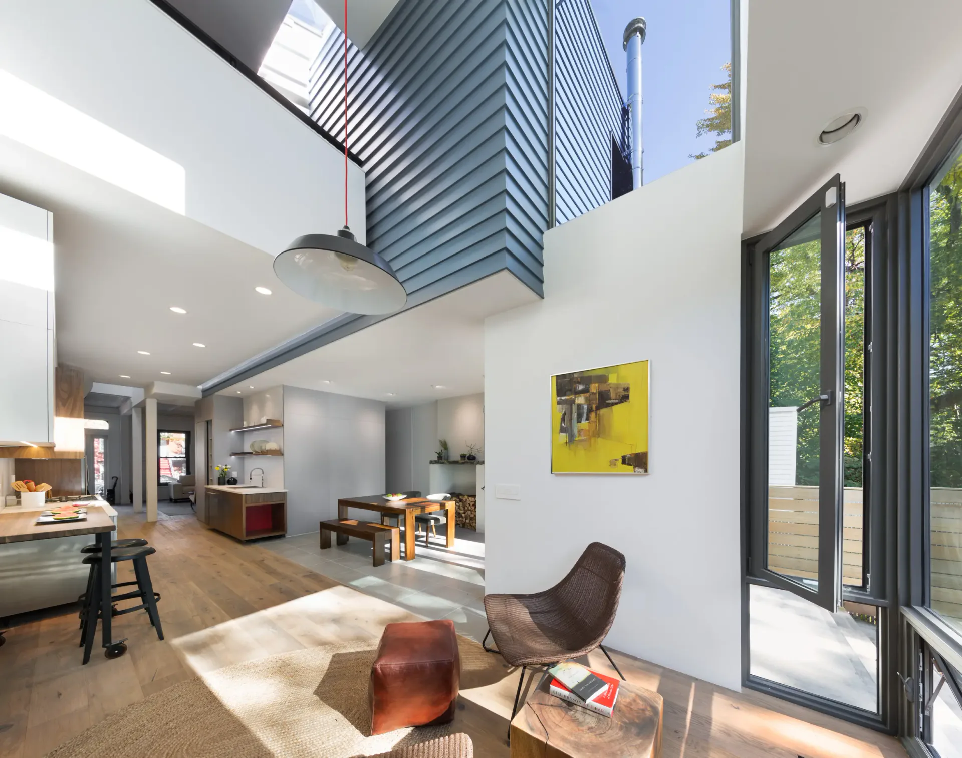 Modern open-plan interior with soaring ceiling, skylights, natural wood flooring, and contemporary furnishings by noroof architects.