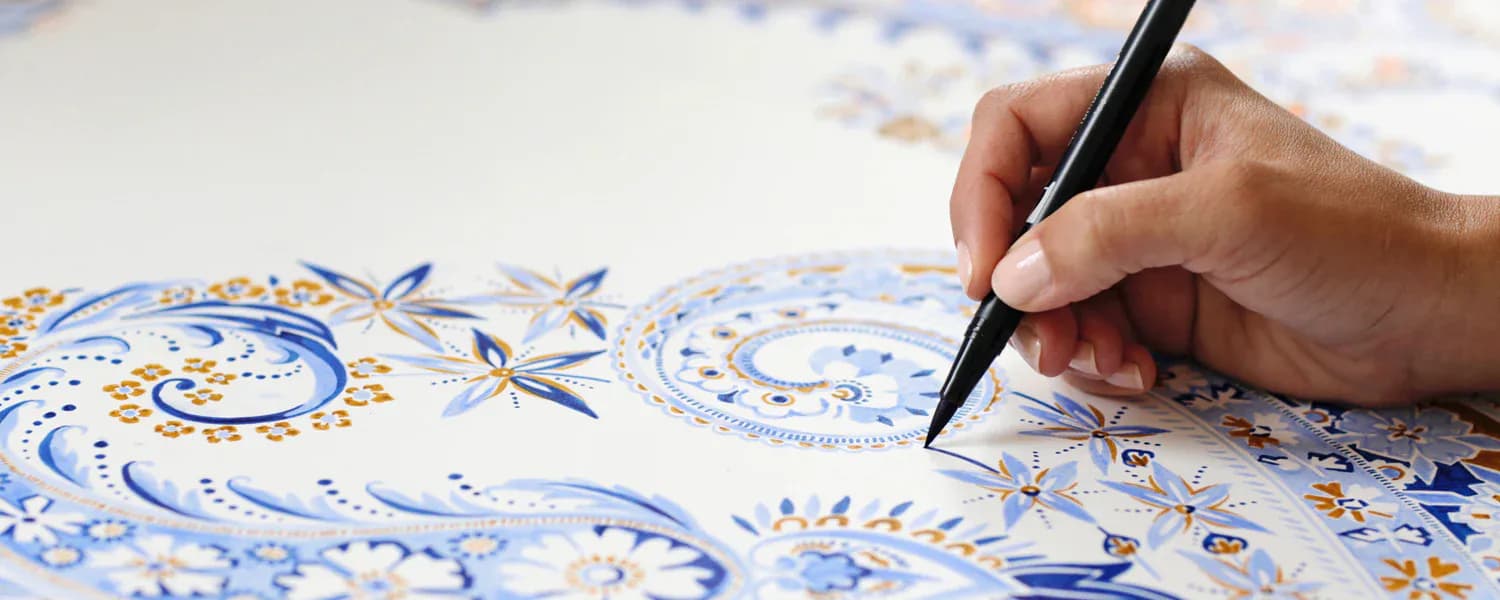 Hand-painted blue and gold decorative pattern on white paper with fine detail work by NuPrimary.