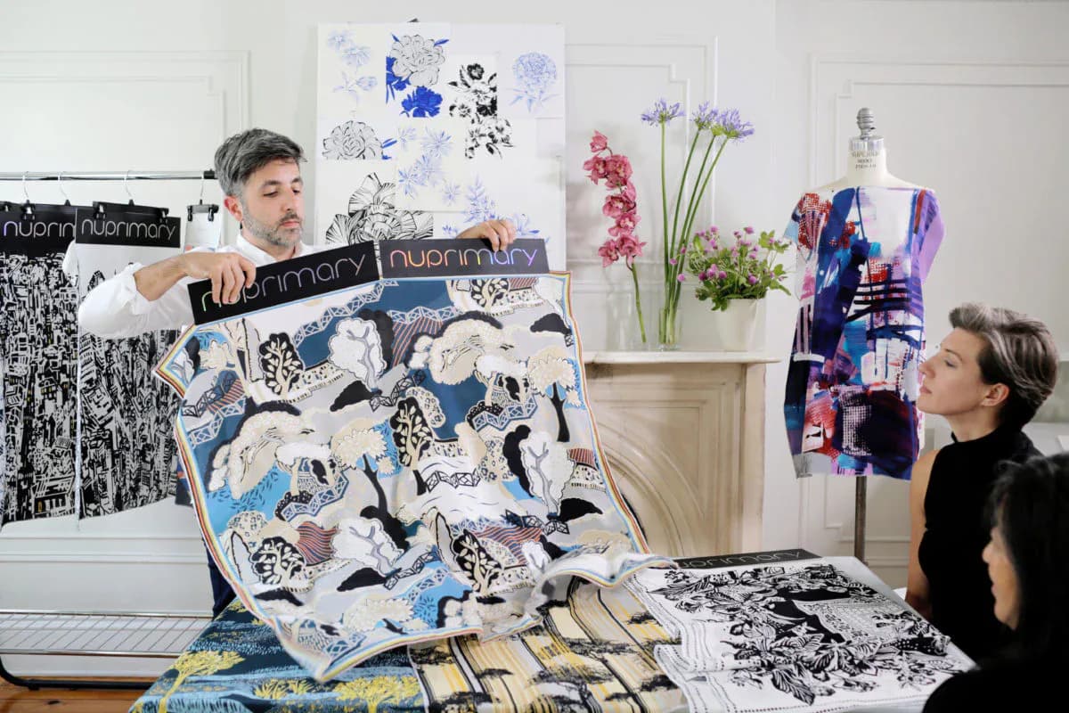 Textile and pattern design studio workspace with fabric samples, botanical illustrations, and design mockups displayed on walls and work surfaces by NuPrimary.
