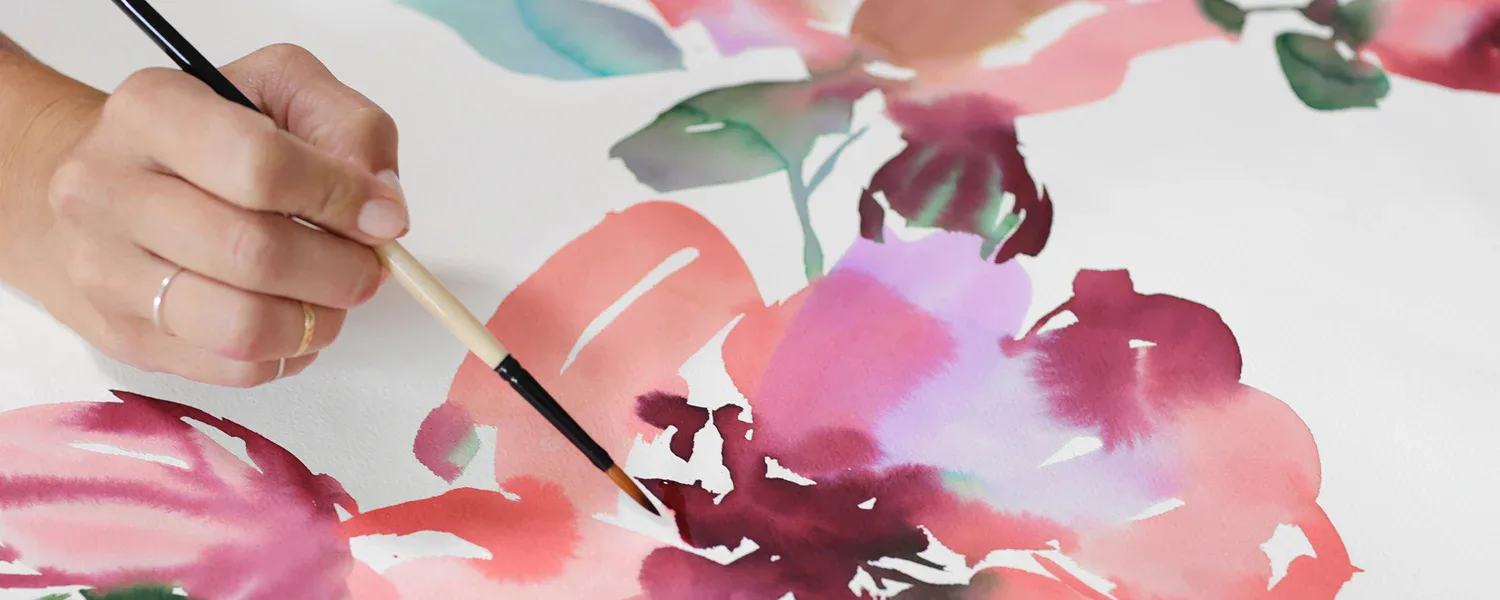 Hand painting abstract watercolor florals in pink and burgundy tones on white paper by NuPrimary.