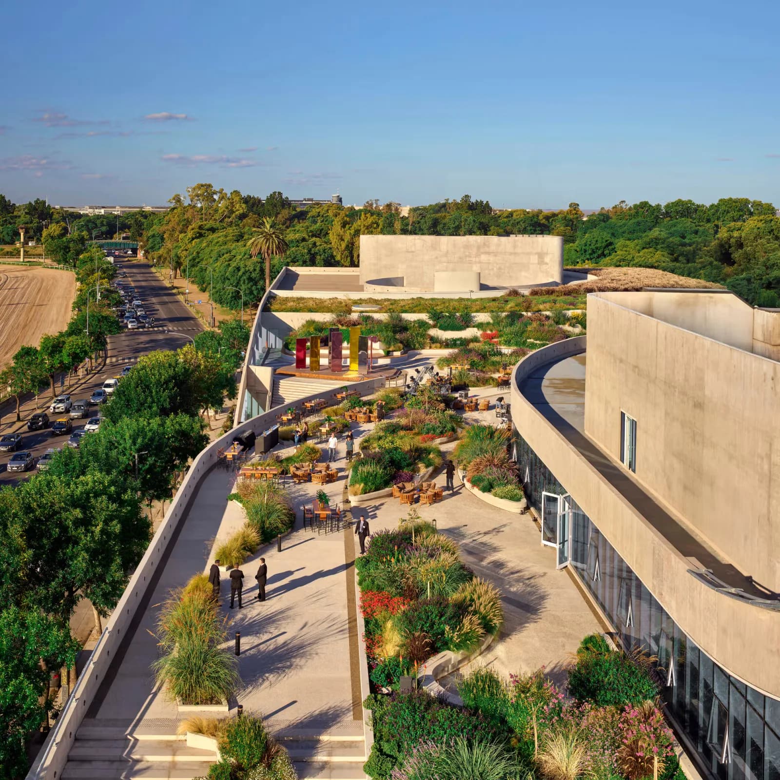 Aerial view of a modern public plaza with curved concrete architecture, landscaped gardens, and gathering spaces surrounded by trees by ODA New York.