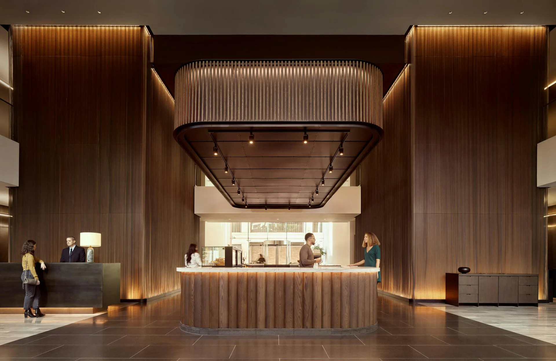 Modern hotel lobby with warm wood-clad walls, central reception desk, and symmetrical architectural framing, designed by Olson Kundig.
