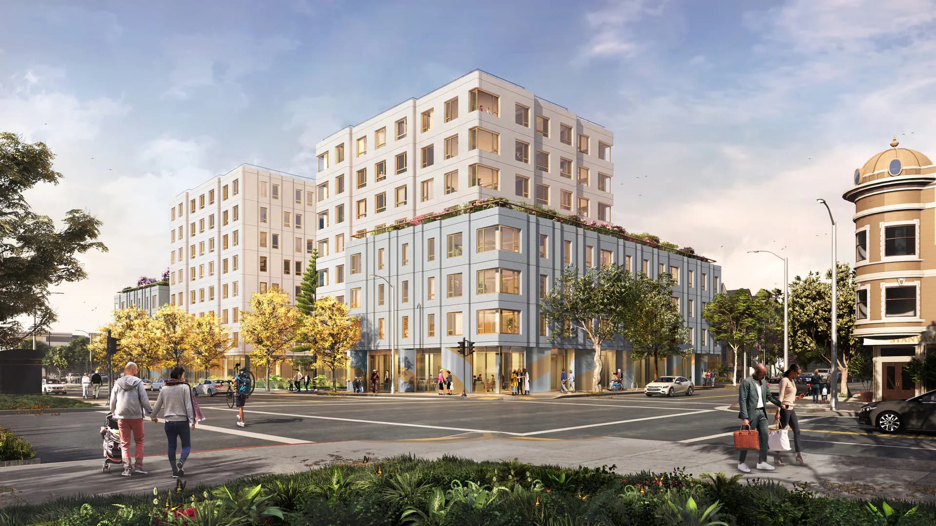 Corner street view of mixed-use urban development with cream-colored residential tower, blue-gray mid-rise building, and golden-domed structure by OMA New York.