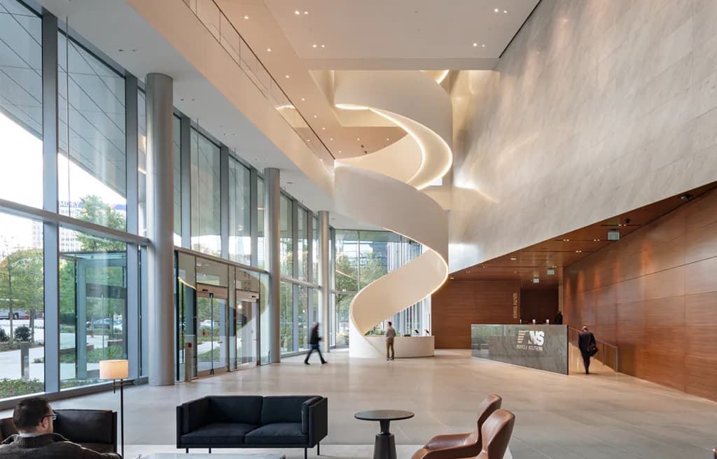 Modern lobby with curved sculptural ceiling element, polished concrete floors, dark seating, and wood-paneled walls, designed by One Lux Studio.