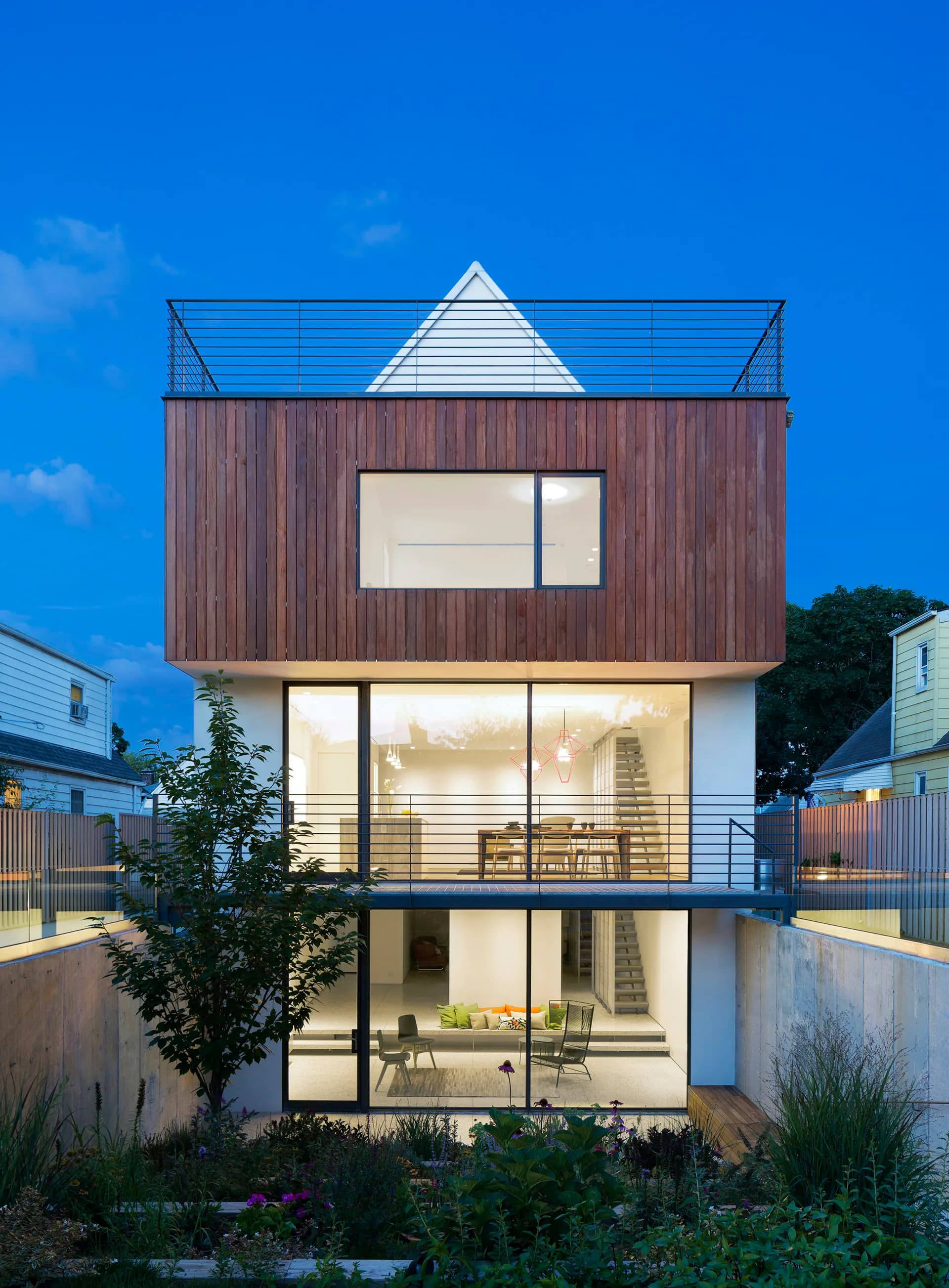 Modern residential building with stacked wood and white volumes, expansive glazing, and geometric roofline against blue sky, by O'Neill Rose Architects.