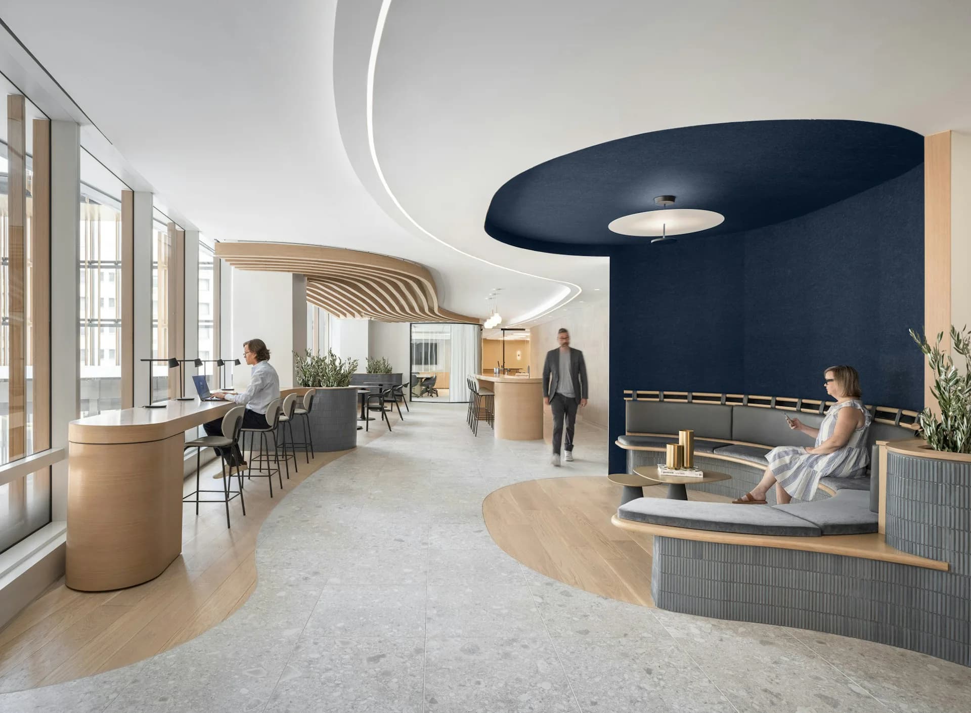 Modern office lobby with curved navy blue wall, light wood accents, curved ceiling details, and synthetic figures; design by OTJ Architects.