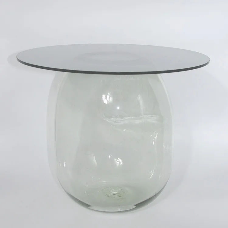 Sculptural glass table with a translucent cylindrical base and flat top surface against a neutral background, by Panorammma.