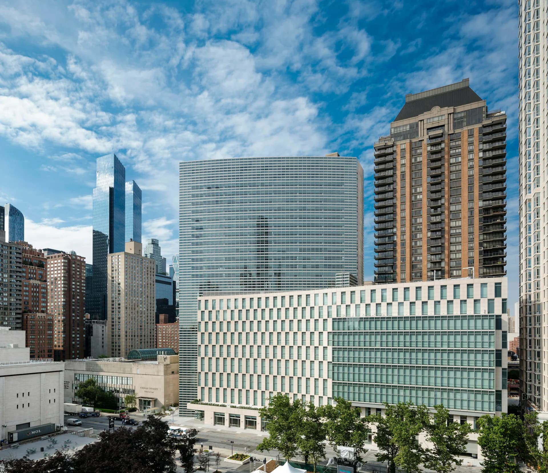 Modern mixed-use building with glass and white stone facade in urban setting, featuring geometric patterned exterior, integrated with surrounding skyscrapers by Pei Cobb Freed & Partners Architects LLP.