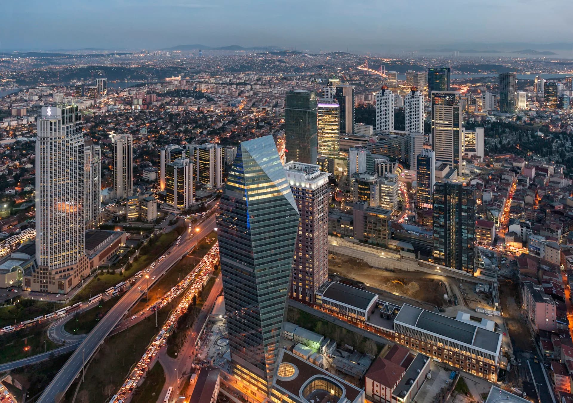 Aerial twilight photograph of a dense urban skyline with illuminated high-rise buildings, rivers, and extensive cityscape by Pei Cobb Freed & Partners Architects LLP.