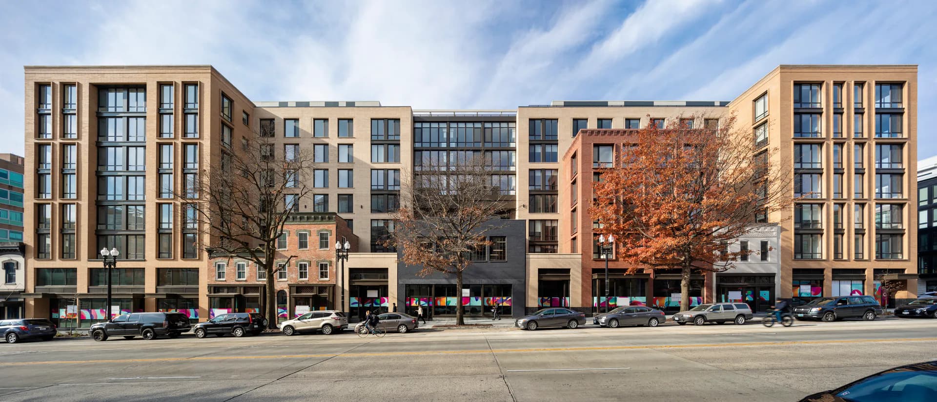 Multi-story mixed-use residential building with brick and stone facade, ground-floor retail, and regular window pattern by Perkins Eastman.