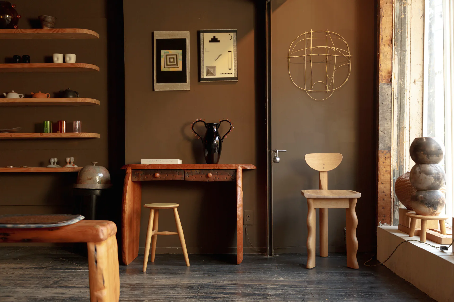 Warm-toned interior with wood furniture, shelving, and sculptural elements in earthy browns and natural materials by Piscina.
