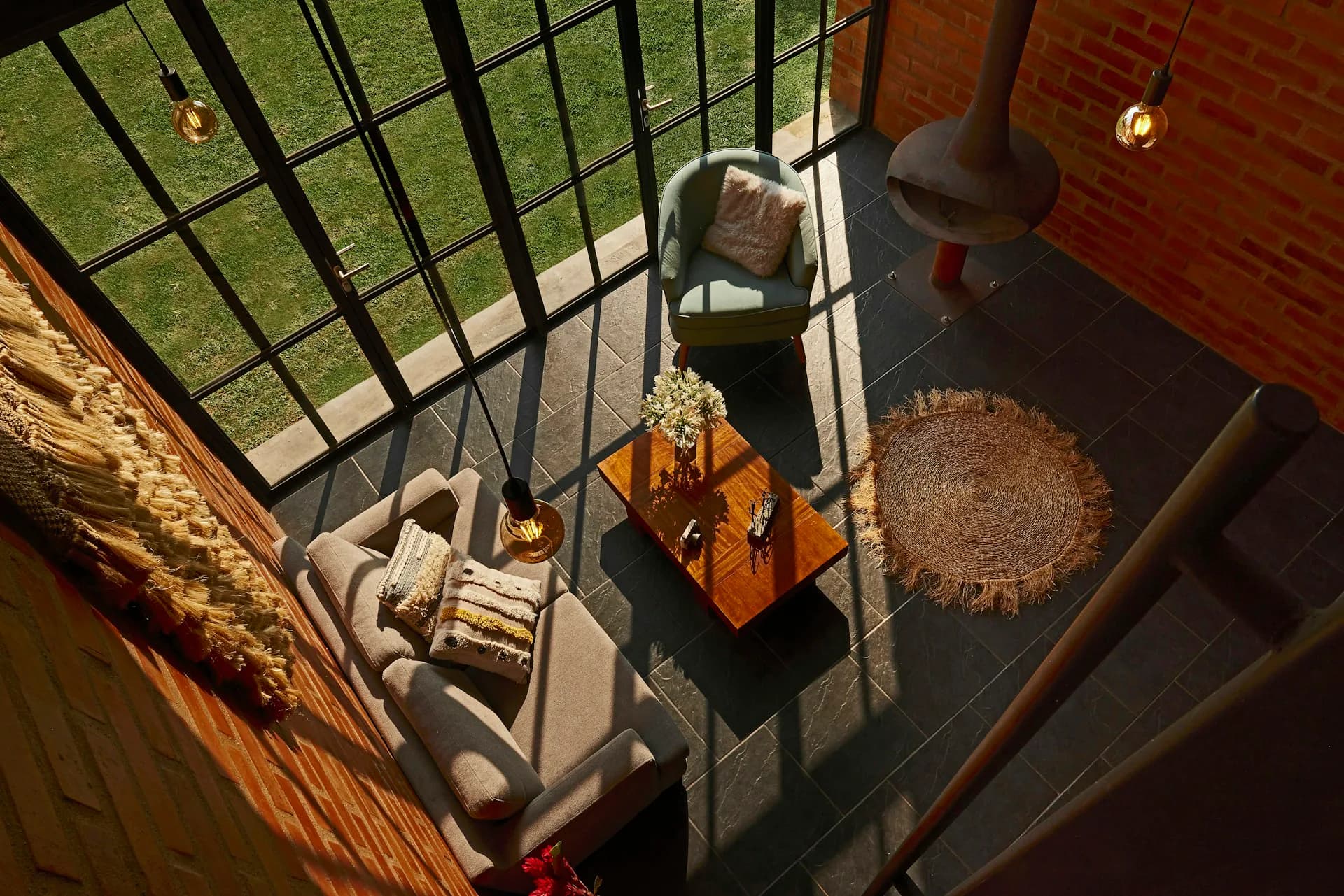 Overhead view of a modern entryway with black steel railings, concrete flooring, wooden accents, and natural light from above by PJCArchitecture.