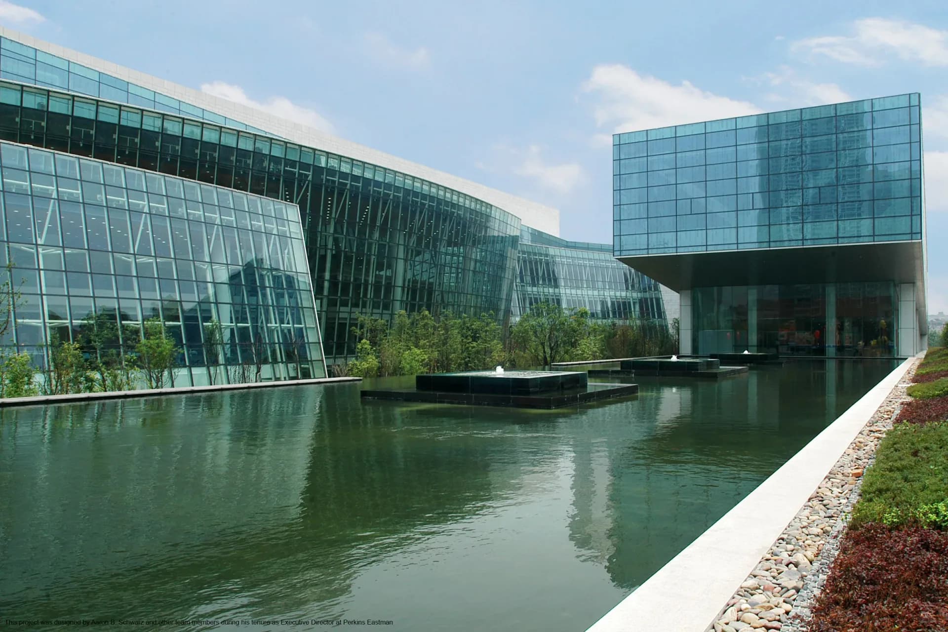 Contemporary waterfront architecture featuring glass and steel buildings reflected in a calm canal, designed by Plan A.