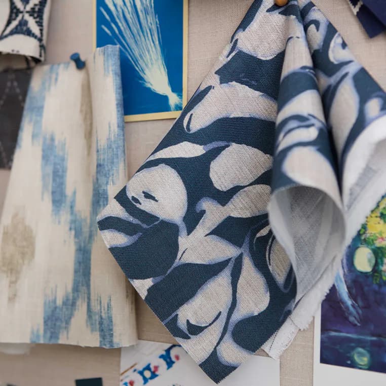 Close-up of blue and white patterned textiles and fabrics displayed together, showcasing coordinated geometric and floral designs by Pollack.