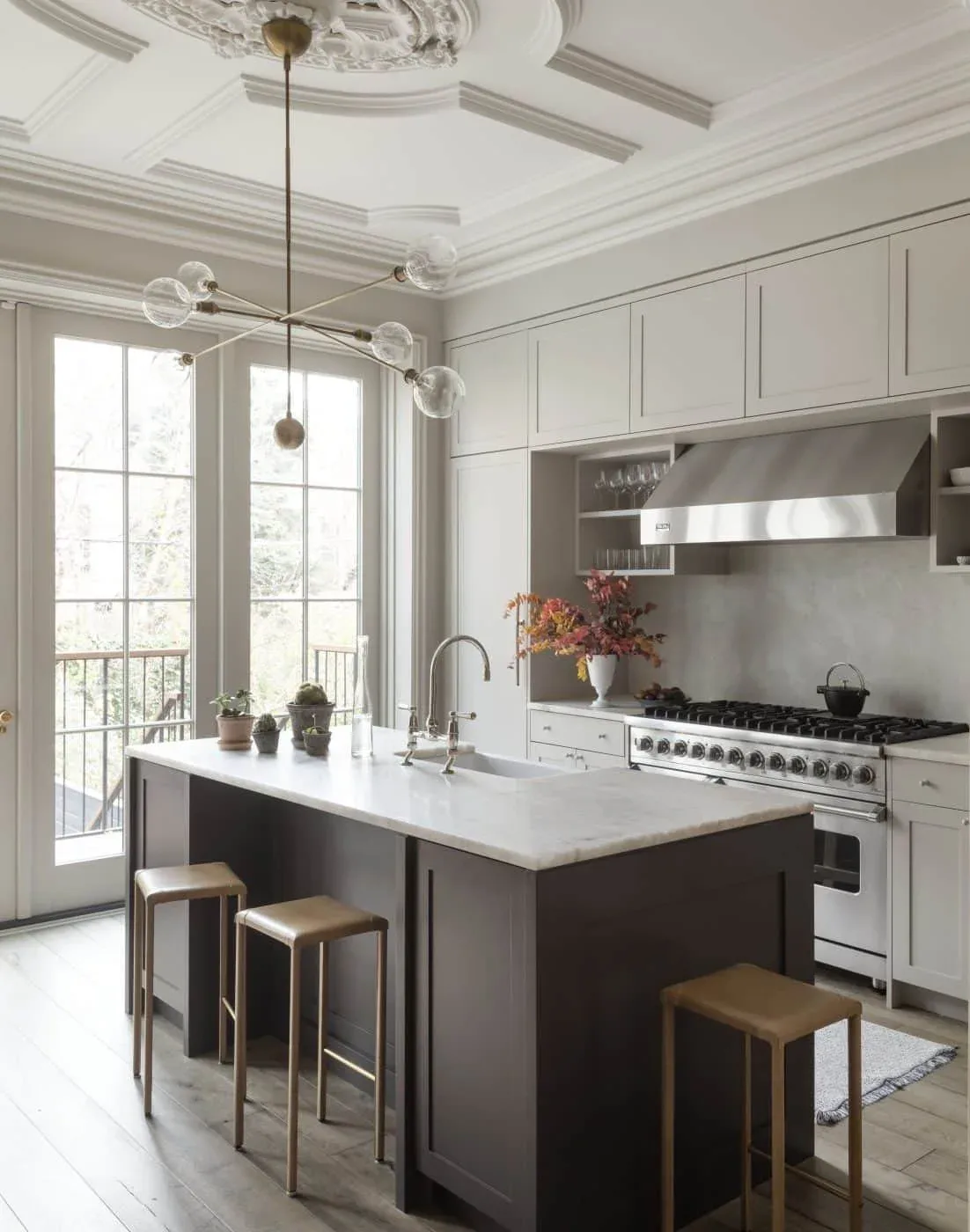 Elegant kitchen with cream cabinetry, dark island with white countertop, stainless steel range, and modern pendant lighting by Prospect Woodworks.