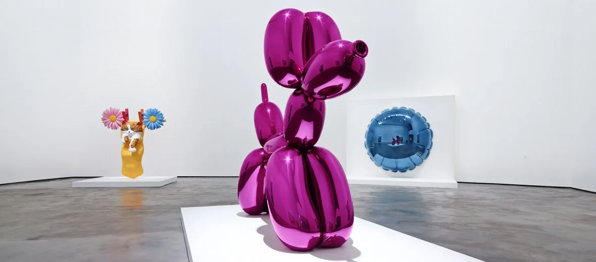 Gallery installation featuring three sculptural artworks: a colorful abstract piece on yellow base, a striking purple balloon-like sculpture in center, and a blue spherical work, by Prototype New York.