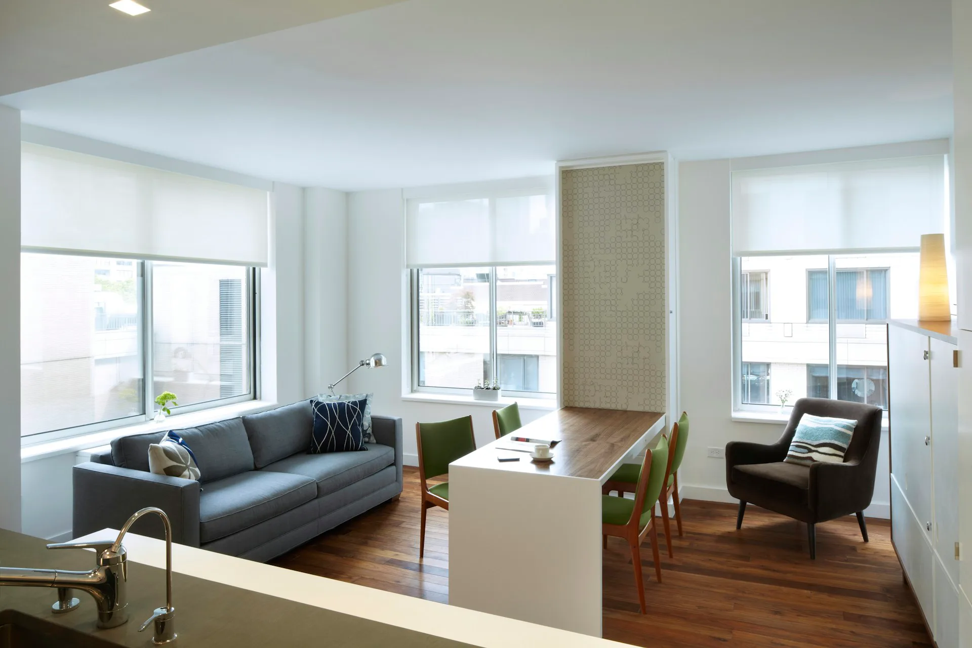 Modern apartment living room with gray sofa, wooden floors, floor-to-ceiling windows, and mid-century furniture by pulltab.