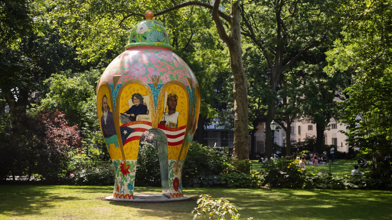 Colorful sculptural installation in a park setting with trees, featuring a yellow and blue dome structure with arched openings by R & Company.