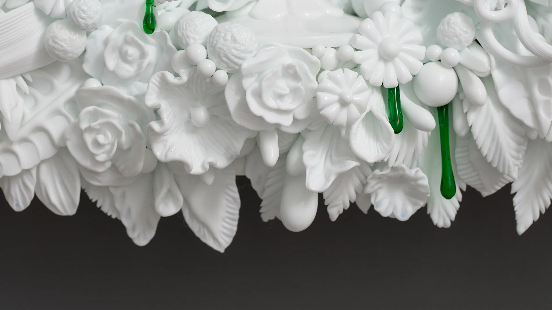 Abundant white flowers with green stems arranged densely against a dark background, creating a striking floral installation by R & Company.