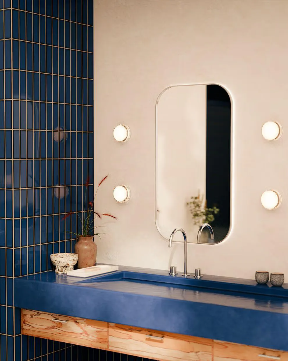 Modern bathroom with navy blue tiled accent wall, floating blue vanity, natural wood base, and illuminated oval mirror by RBW.