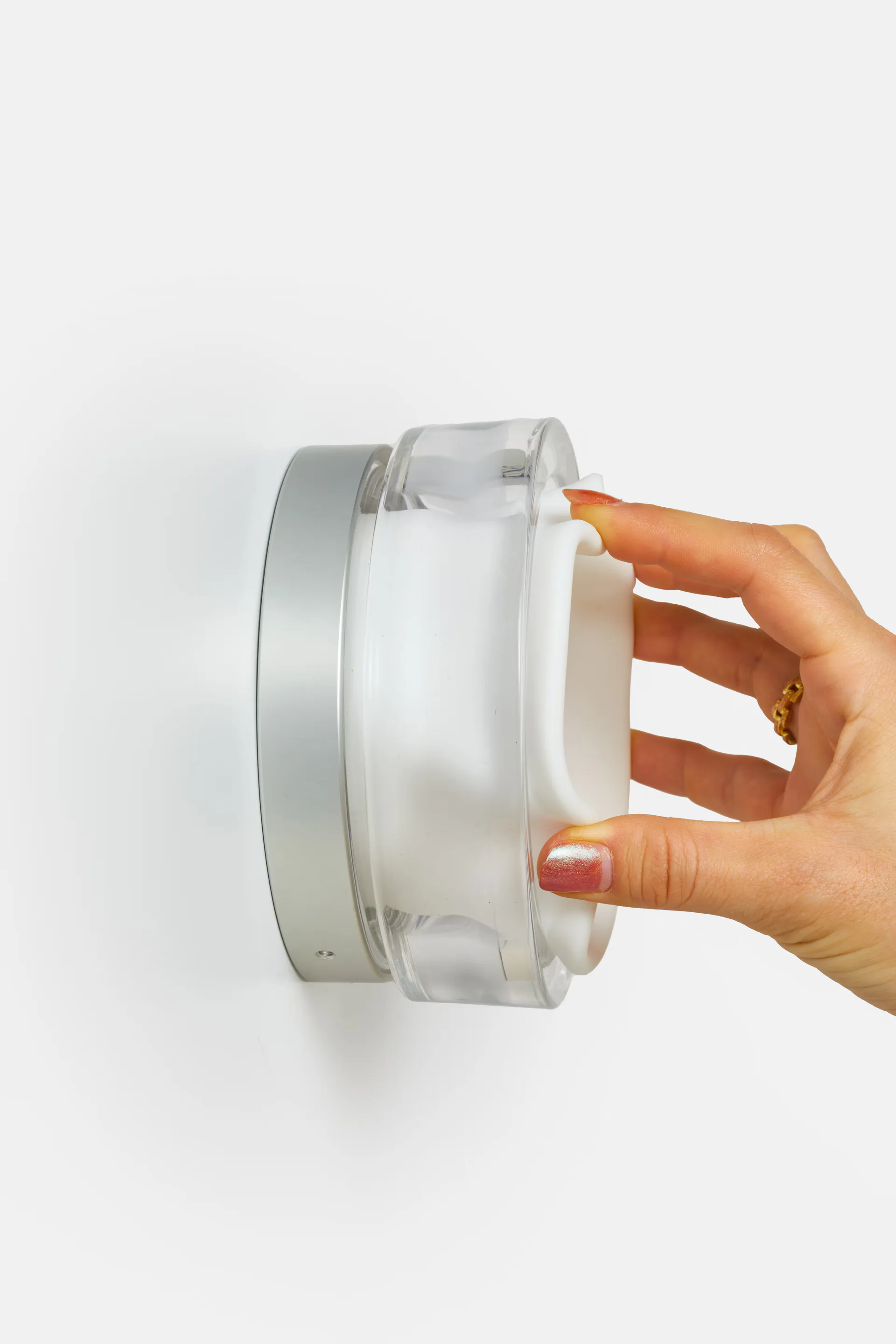 Hand holding a translucent white cylindrical product with metallic accents against a neutral background, showcasing industrial design by RBW.