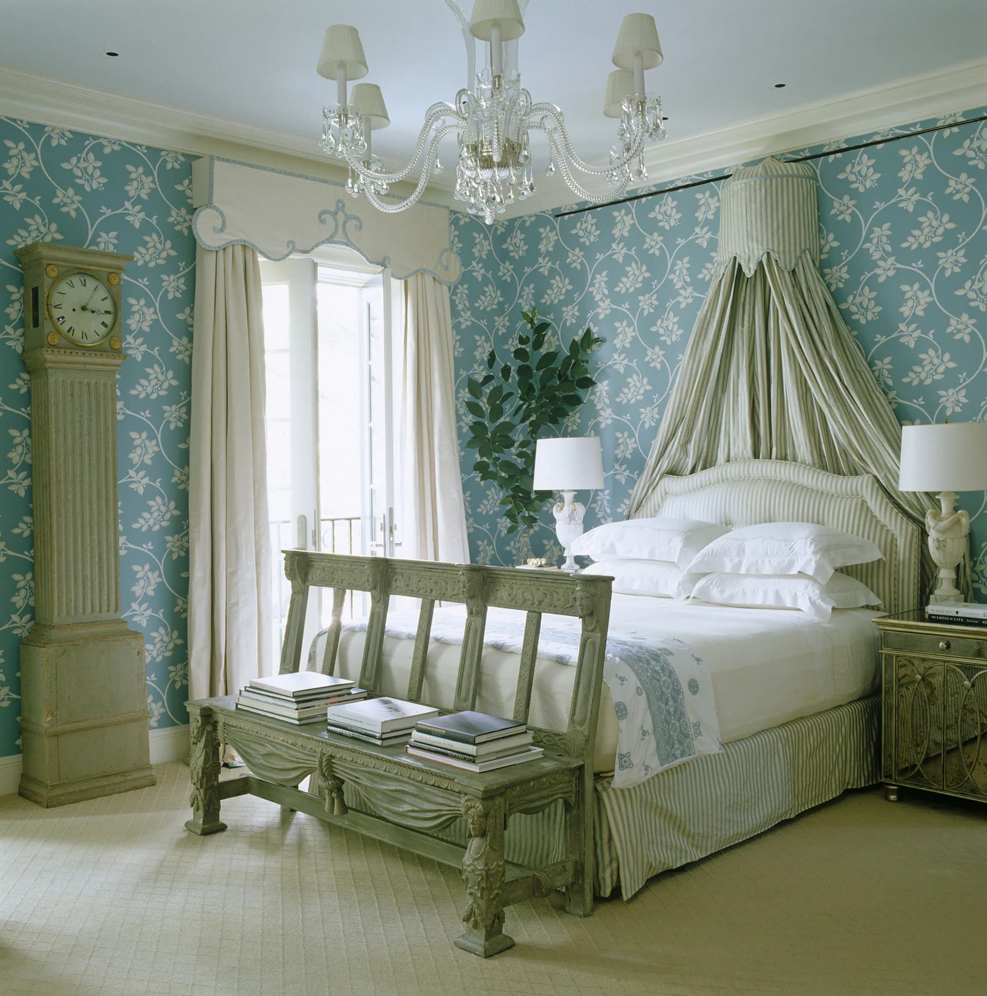 Elegant bedroom with teal floral wallpaper, green canopy bed with striped fabric, crystal chandelier, and matching green furnishings by Redd Kaihoi.