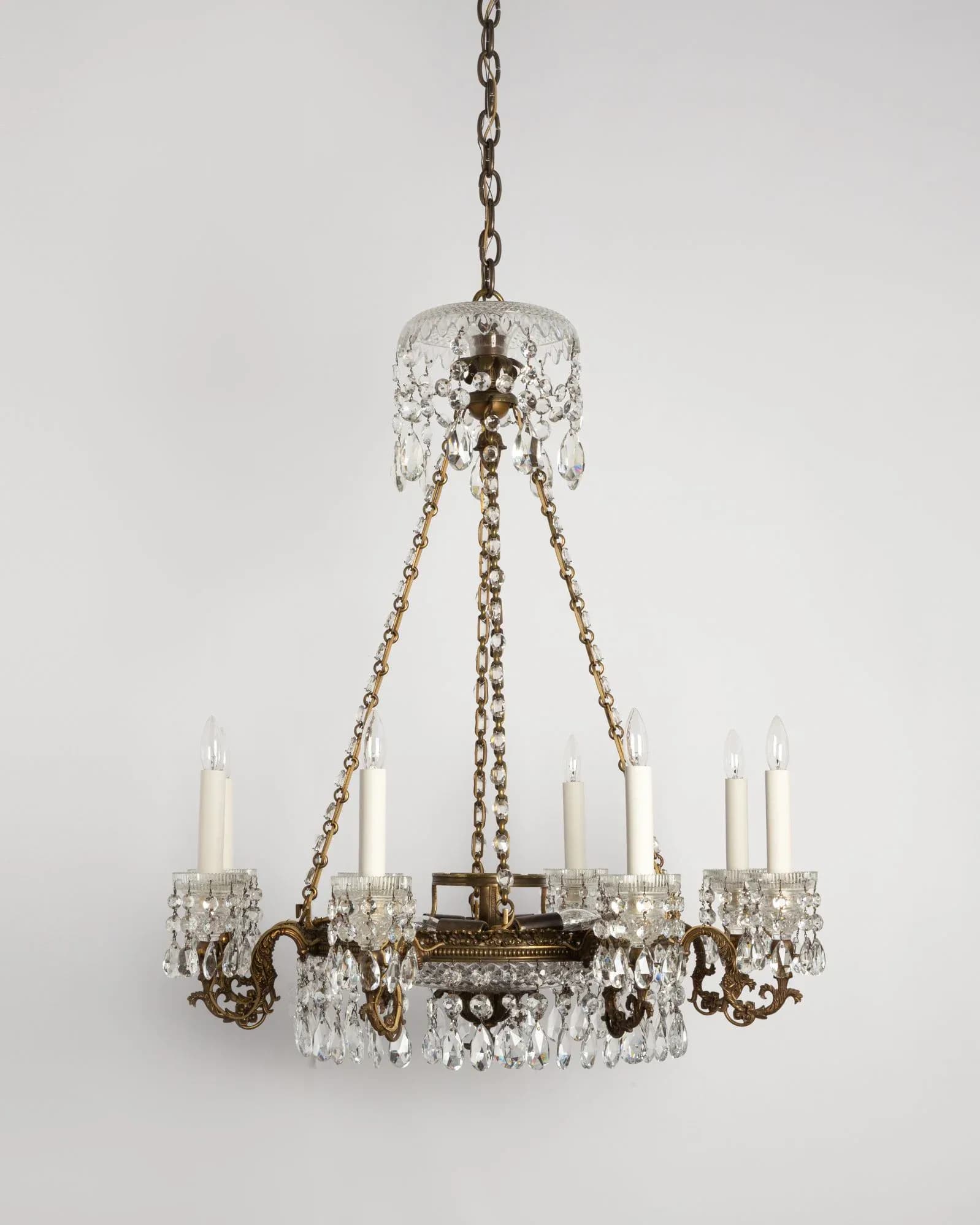 Ornate brass and crystal chandelier with eight candle arms and draped crystal prisms, suspended by chain by Remains Lighting Company.
