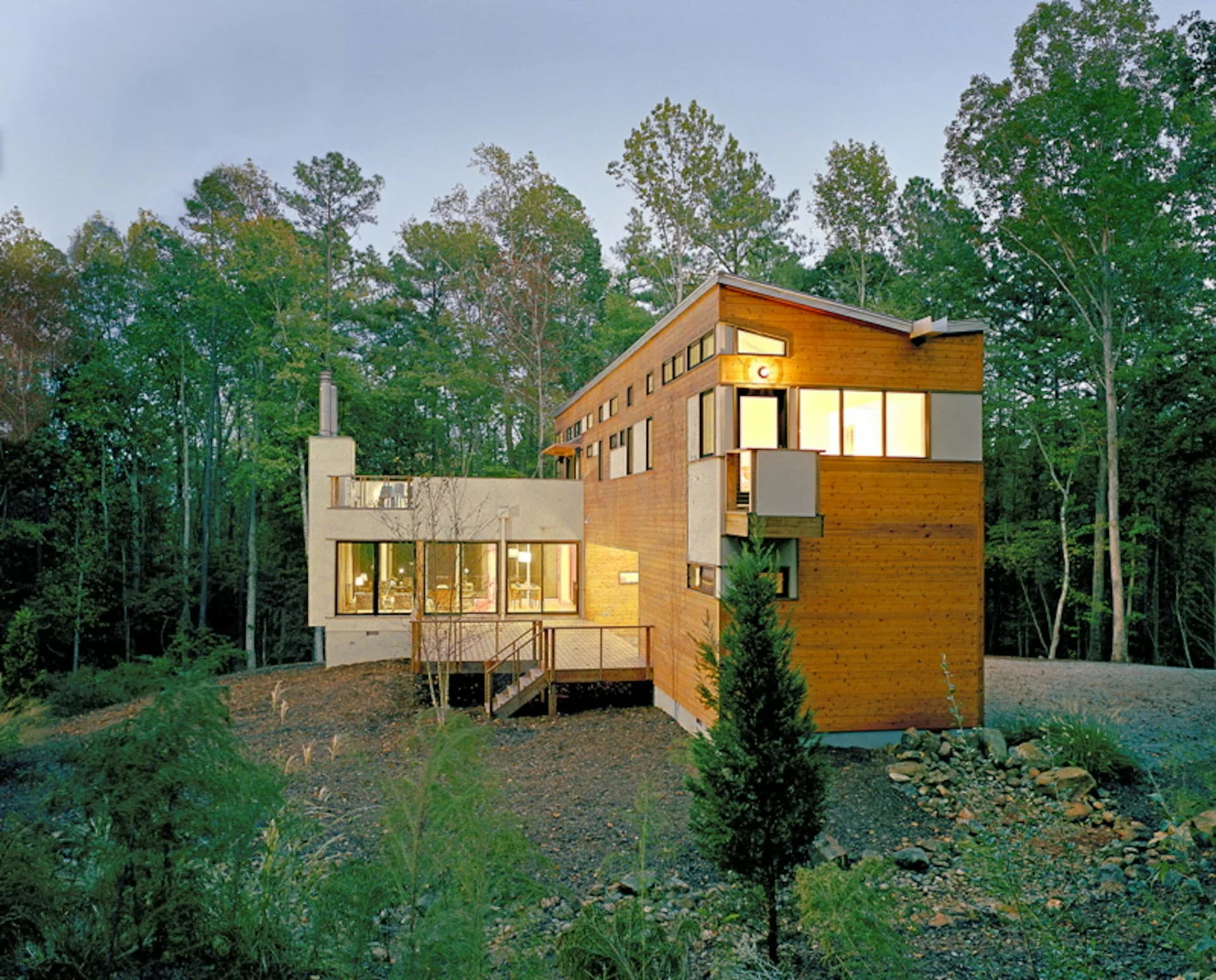 Modern wooden residential building with glass windows nestled in a forested setting, featuring clean lines and elevated foundation by Resolution: 4 Architecture.