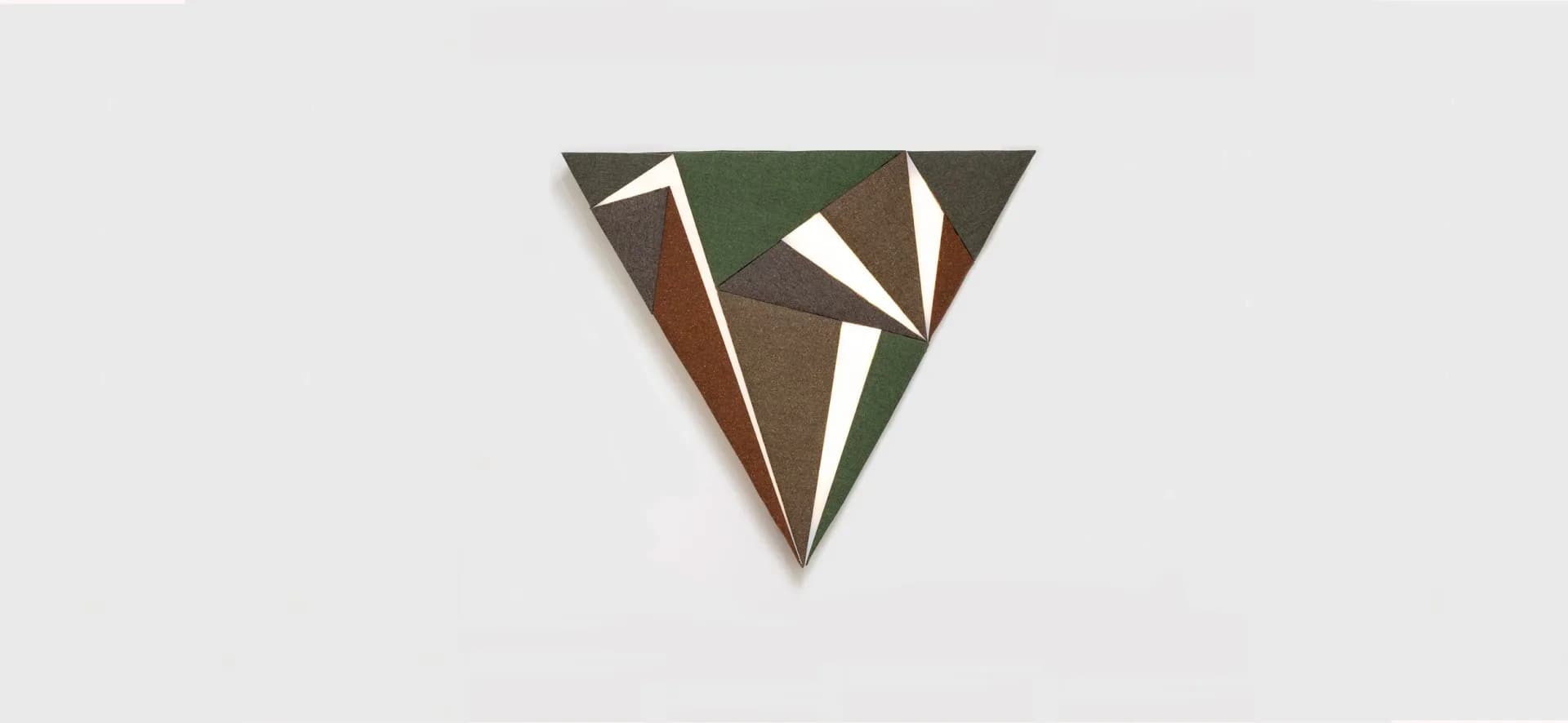 Geometric wall art installation with interlocking triangular panels in earthy tones of olive, brown, and cream by Rhyme Studio.