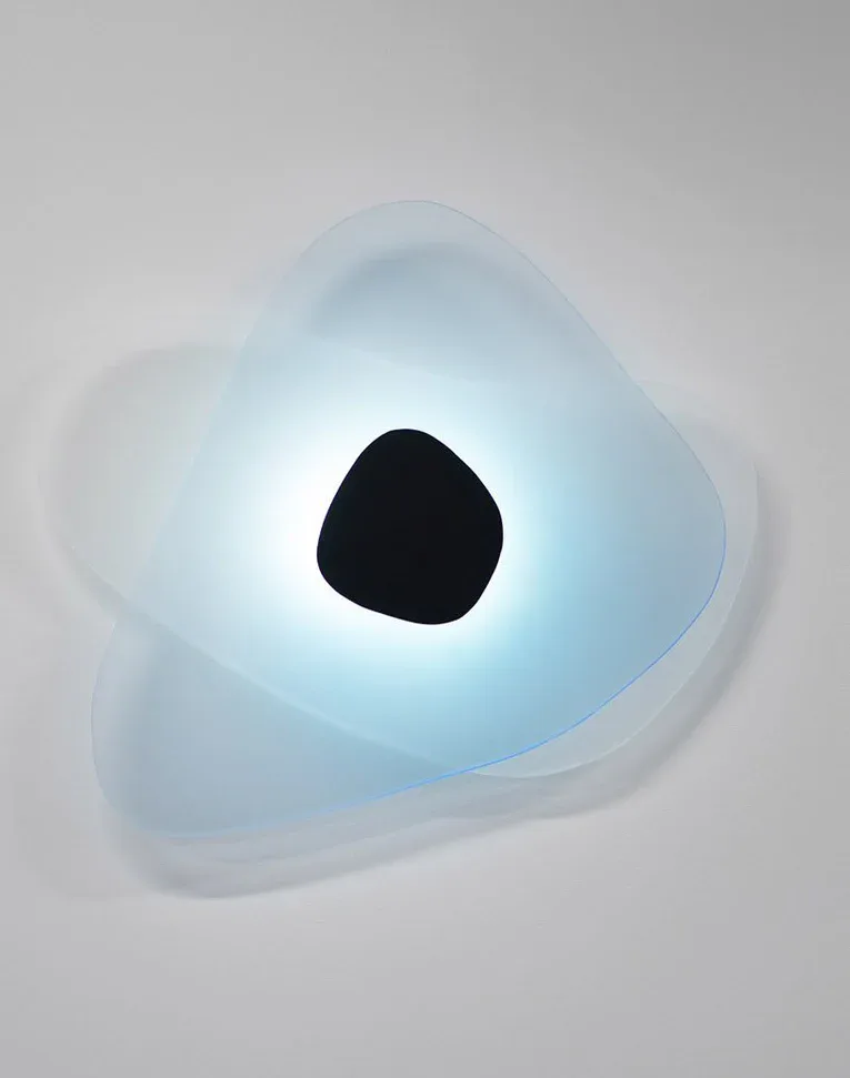 Abstract sculptural form with translucent blue-tinted surfaces and a dark spherical element, creating an ethereal lighting installation by Richard Clarkson Studio.