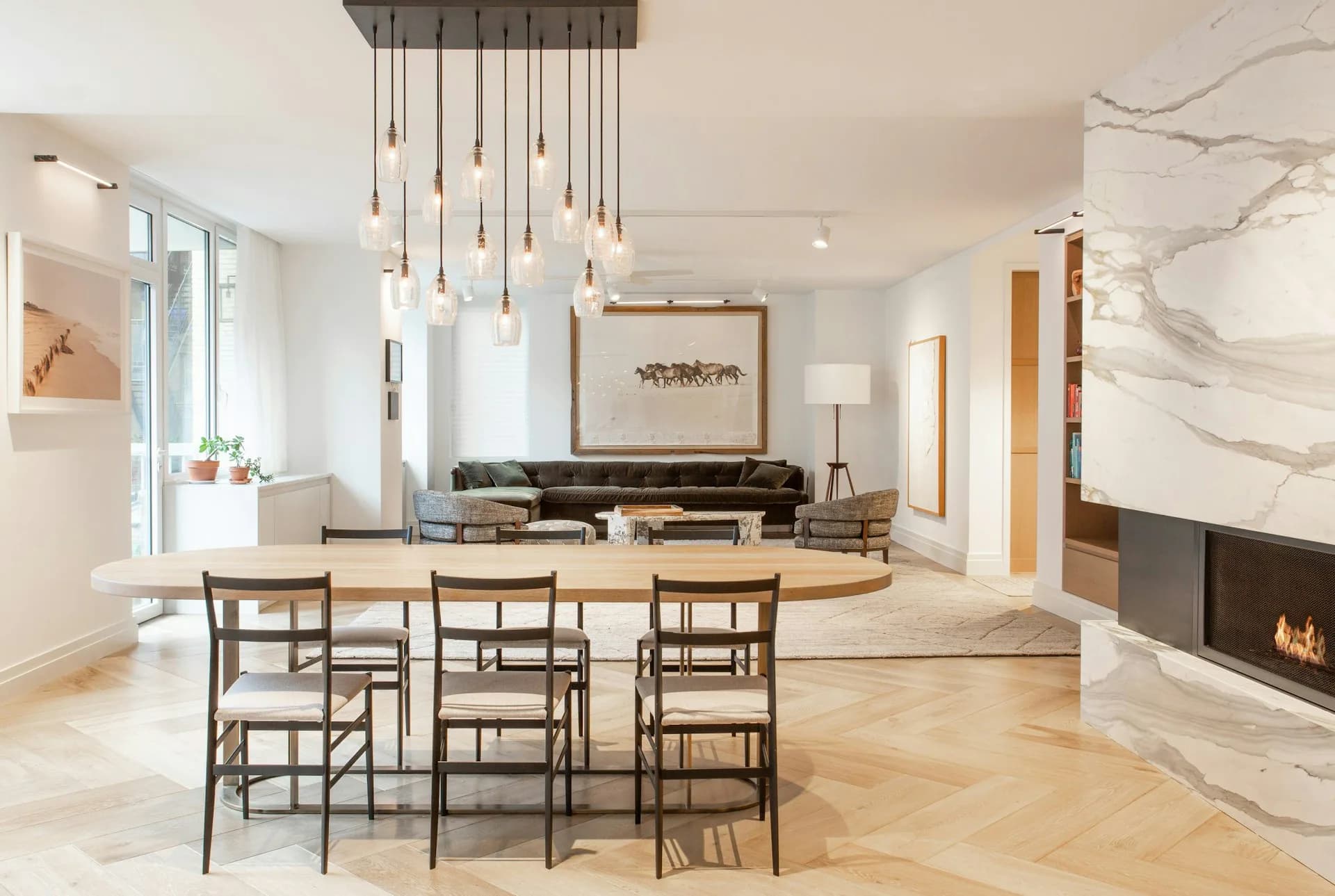 Bright, minimalist dining space with wood dining table, woven chairs, pendant lighting, marble fireplace, and modern furnishings by Rise Projects.