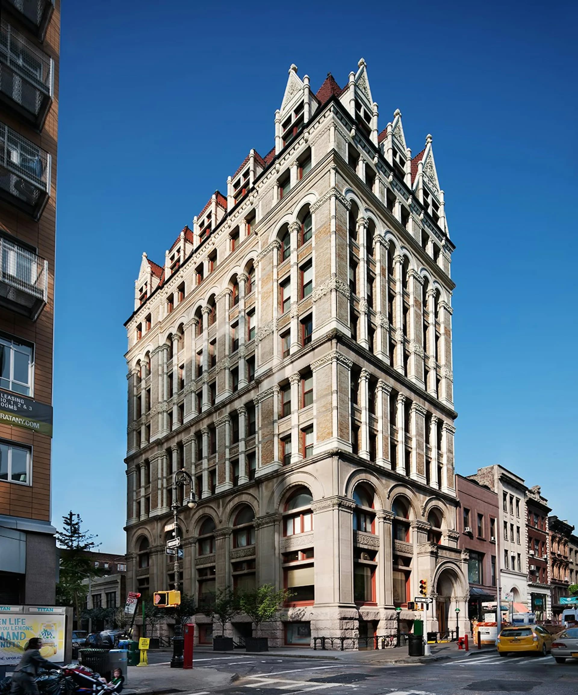 Ornate historic corner building with cream and brick facade, arched ground-floor windows, and distinctive peaked roofline, by RKTB Architects, P.C.