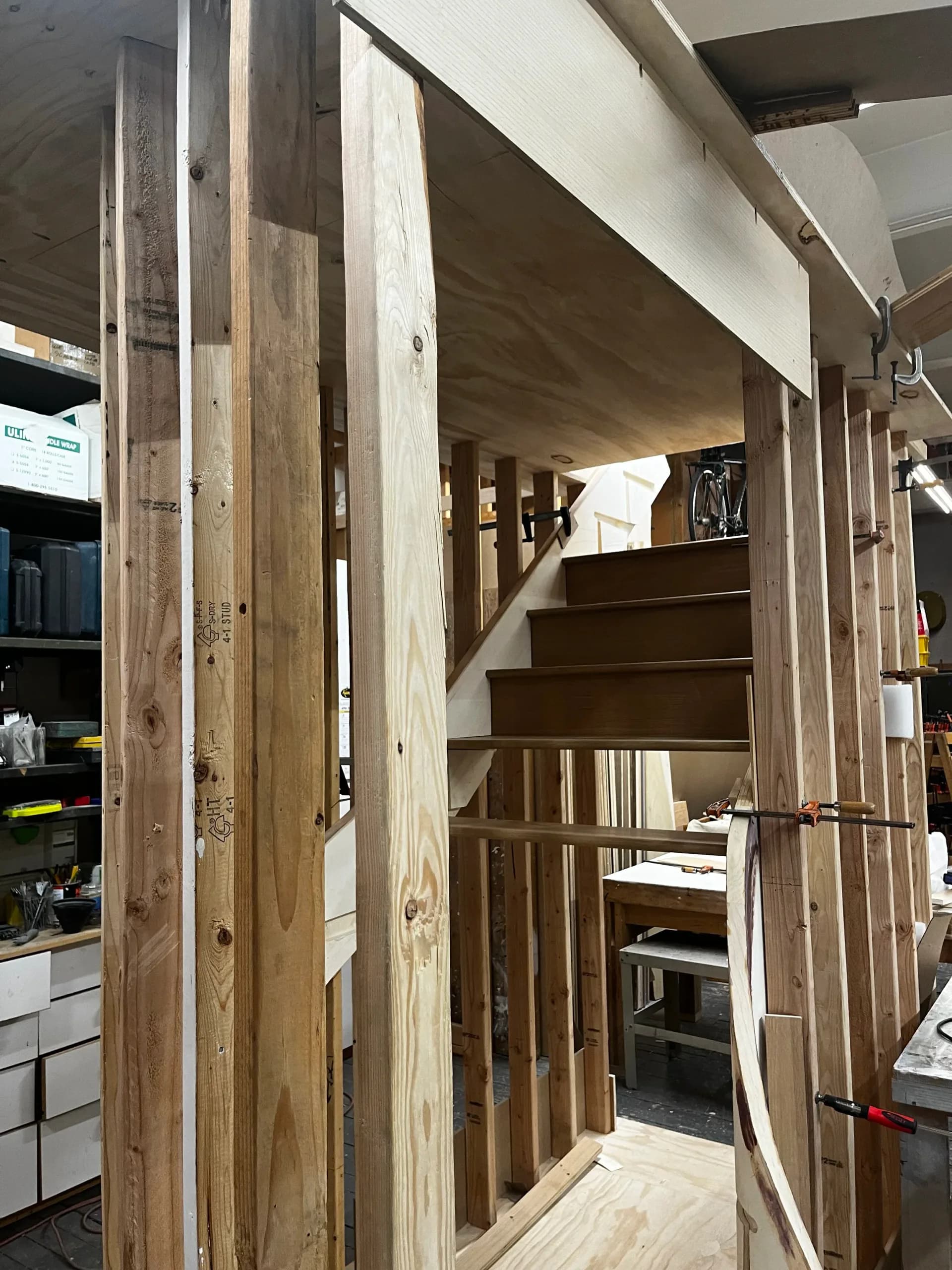 Custom wooden staircase with natural wood framing and built-in storage shelving, showcasing joinery and craftsmanship by Robert Kalka Custom Woodworking.