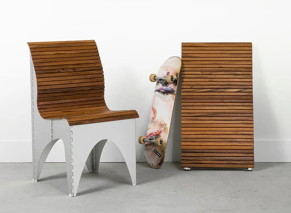 White and wood furniture installation featuring a curved lounge chair, skateboard, and wooden panel wall against concrete flooring by RockPaperRobot.